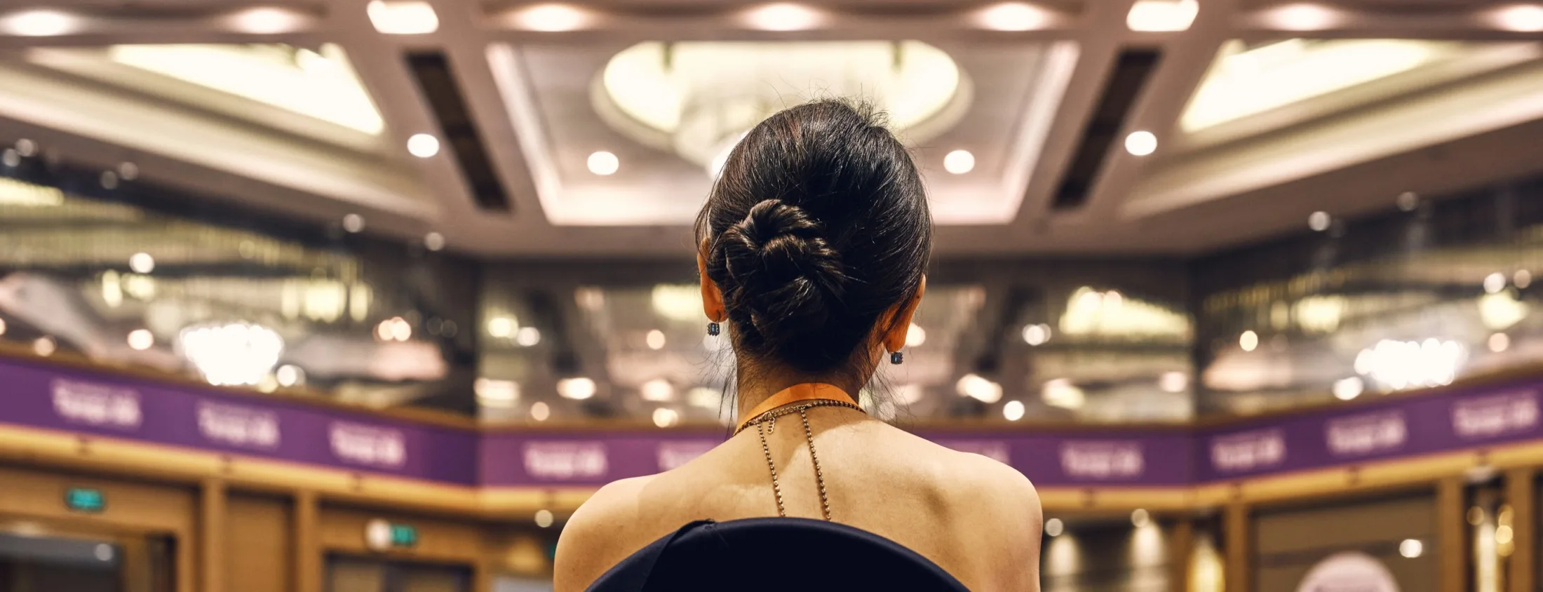 An attendee seated in a grand ballroom before a session begins, chandeliers overhead